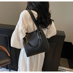Chic black leather bucket bag with unique metal ring handle shown on a model