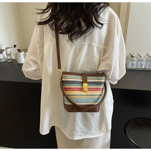 Detail showing colorful woven stripe texture and gold magnetic clasp on the bucket bag