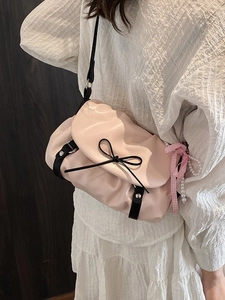 Sac nuage rose avec noeud noir et chaîne de perles sur une robe blanche élégante