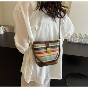 Detail of multi-color woven bucket bag with brown leather base and golden metal buckle