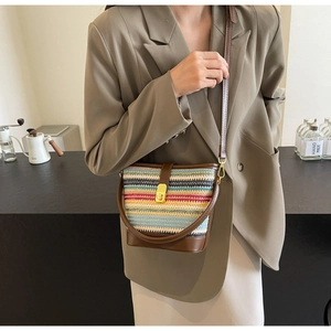 Detail of multi-color woven bucket bag with brown leather trim and golden metal lock