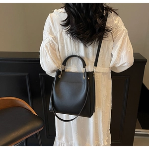 Detail showing high-quality black matte leather texture and gold metal handle of this tote