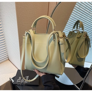 Detail of light green faux leather bucket bag with top handles and gold-tone hardware