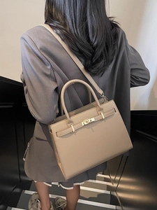 Elegant beige leather handbag with gold buckle shown by a model for a chic look