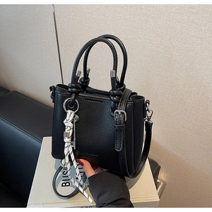 Détail du sac seau noir en cuir grainé avec breloque en corde tressée et clé en métal