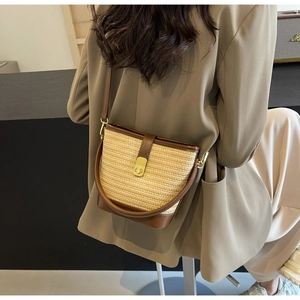 Straw bucket bag with brown leather trim and gold lock shown on model outfit