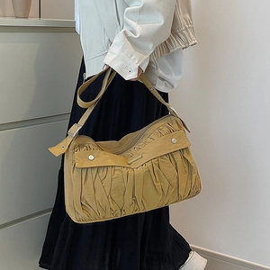 Détail de la texture plissée du sac à main jaune moutarde avec rivets en métal argenté