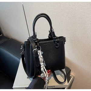 Détail d'un sac seau en cuir grainé noir avec pendentif en corde tressée et cloche