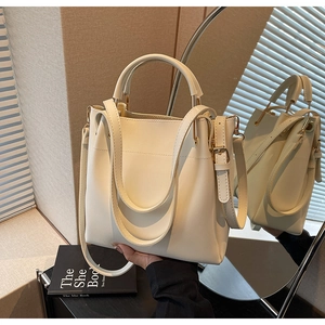 Detail of minimalist cream bucket bag with detachable strap and smooth faux leather finish