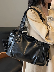 Minimalist black leather tote bag with silver rivets and metallic ring handle details
