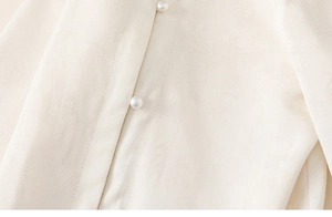 Close-up of ivory Chinese style shirt featuring floral jacquard fabric and pearl buttons