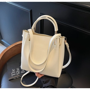 Detailed close-up of cream leather bucket bag with gold hardware and dual handles