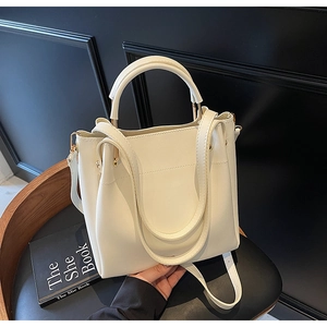 Detailed close-up of cream faux leather handbag with soft texture and golden hardware