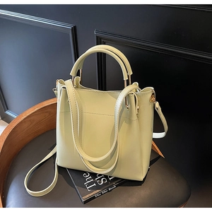 Detail view of mint green bucket handbag with dual handles on a black leather chair