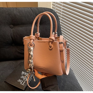 Vue détaillée du sac seau rose en cuir grainé avec poignées à nœuds et logo gravé