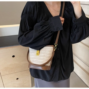 Detail showing the woven texture of the beige handbag with brown leather trim and gold lock