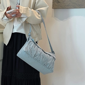 Détail du sac à bandoulière bleu clair plissé avec tissu texturé porté par un mannequin