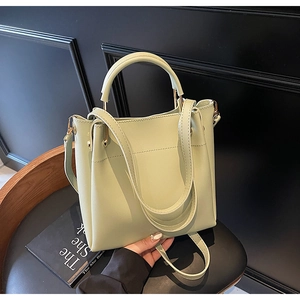 Detail of mint green PU leather bucket bag with gold hardware and cylindrical handle