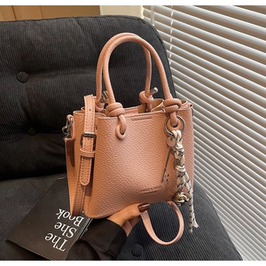 Détail du sac seau rose en cuir grainé avec breloques métalliques et poignée ronde