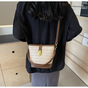 Detailed look at woven bucket bag with leather strap and gold clasp on a model