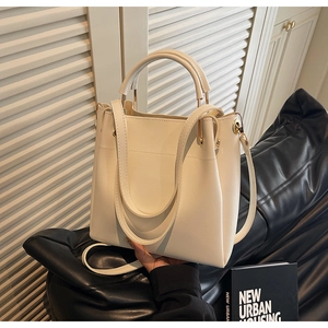 Close-up of cream white leather bucket bag showing golden hardware and handle detail