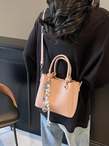 Sac seau en cuir litchi rose pour femme avec foulard porté sur le dos du modèle