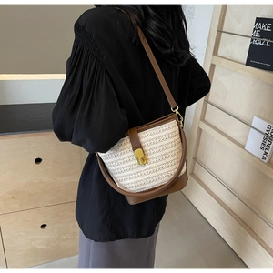 Detail of vintage woven bucket bag featuring brown leather trim and gold metal clasp