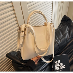 Detail of white leather bucket bag featuring a detachable shoulder strap and matte finish