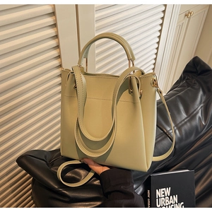 Detail view of light green bucket bag showing the matte leather texture and metal eyelets