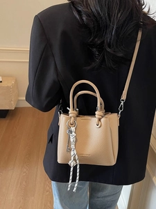Sac seau femme en cuir beige avec poignées et bandoulière réglable dans un décor moderne