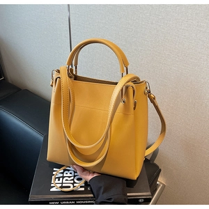 Close-up of ginger yellow bucket bag with metal rings and adjustable shoulder strap