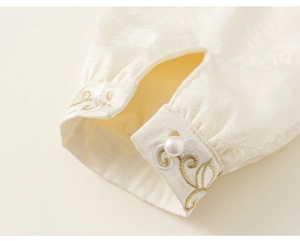 Detail of white silk sleeve with gold embroidery and pearl button on Chinese dress