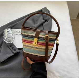 Close-up of woven bucket bag featuring multicolor stripes and brown leather trim