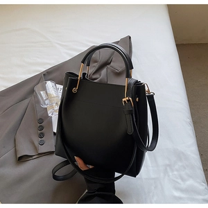 Detail of black leather bucket bag with gold metal ring handle and adjustable strap