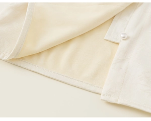 Close-up of beige traditional vest featuring jacquard texture and a pearl button closure
