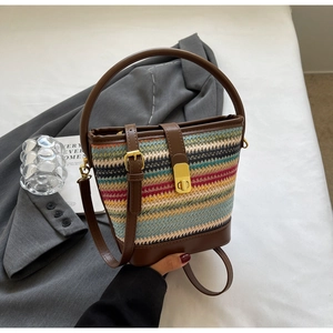 Close-up of multicolored woven bucket bag with brown leather handles and gold buckle detail