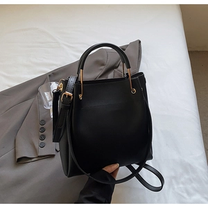 Detail view of black matte leather bucket bag with golden hardware and adjustable strap