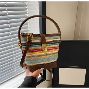 Detail of color striped woven bucket bag featuring brown leather strap and gold buckle