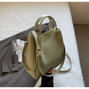 Detail view of light green minimalist bucket bag with golden metal handle and smooth leather