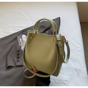 Detail view of light green bucket bag with gold metal handle and soft matte PU leather texture