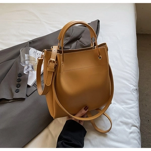Detail of a mustard yellow leather bucket bag with top handle and adjustable shoulder strap