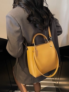 Chic yellow leather bucket tote bag with metal handles and shoulder strap for women