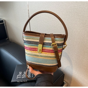 Close-up of colorful straw bucket bag featuring leather handle and metallic clasp