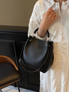 Minimalist black bucket bag with gold metal ring handle and adjustable strap for women