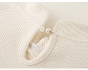 Detail eines Strickkleid-Ausschnitts mit eleganter Perlenschnalle und Tropfenausschnitt