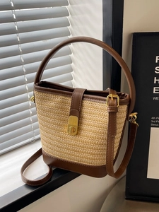 Minimalist straw bucket bag with dark brown leather trim and golden twist lock closure