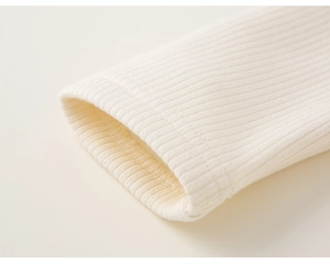 Nahaufnahme der cremefarbenen Strickkleid-Manschetten mit Rippenstruktur und flachen Nähten