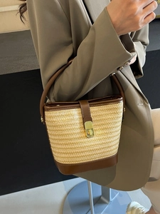 Minimalist beige woven bucket bag with brown leather trim and golden metal lock