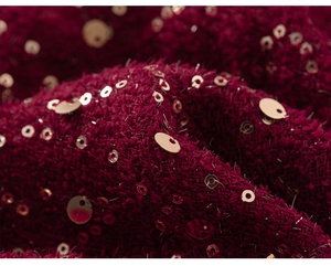 Dettaglio del tessuto a maglia felpato rosso vino con paillettes d'oro lucide