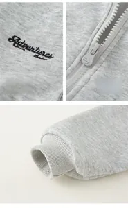 Detail of grey kids hoodie showing Adventures embroidery, zipper and ribbed cuff texture